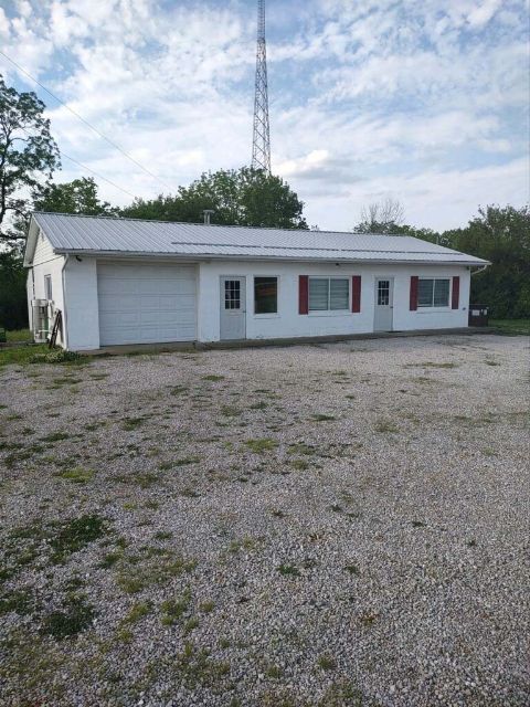 Deercreek Township office, a white single-story building with a garage door and red shutters on a gravel lot